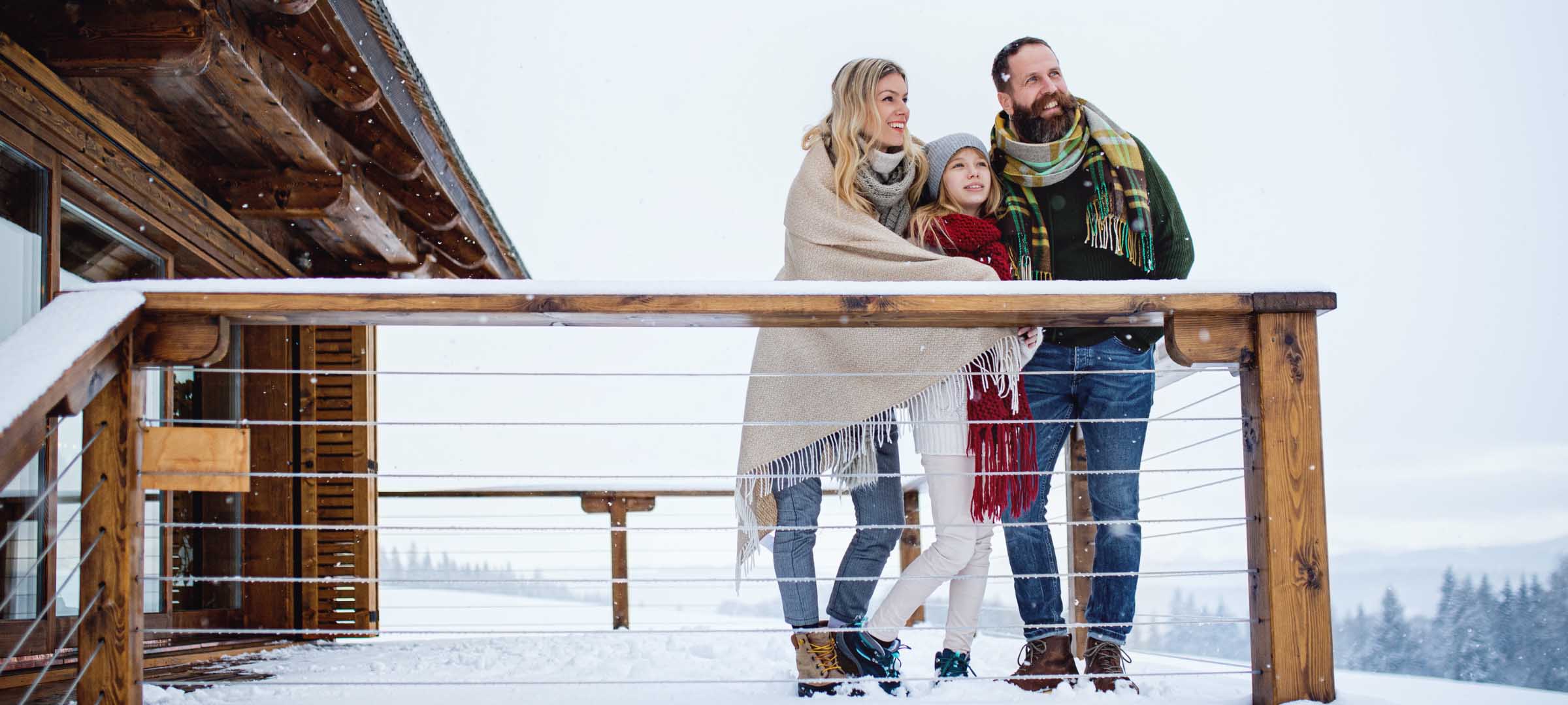 Family enjoying a winter moment on a snowy cabin balcony 